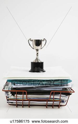 Stock Photography - Trophy over stack of folders against white background. Fotosearch