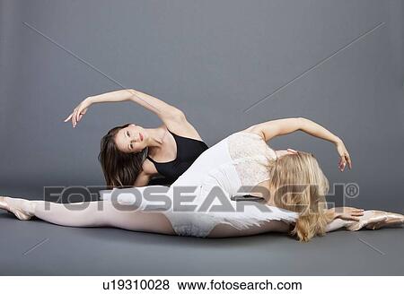 Stock Photo - Two young female ballet dancers doing the splits over grey background. Fotosearch
