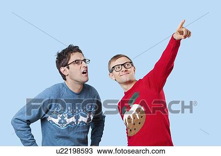 Stock Image - Two young men looking up against blue background. Fotosearch