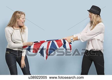 Two young women playing tug of war with British flag against light blue background View Large Photo Image Stock Photography - Two young women playing tug of war with British flag against light blue background. Fotosearch