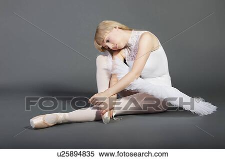 Stock Photography - Upset young female ballet dancer sitting over grey background. Fotosearch