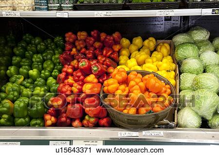 Stock Image - Variety of bell peppers on display for sale in market. Fotosearch