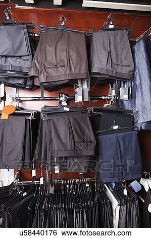 Stock Photograph - Variety of formal pants hanging on hanger at store. Fotosearch