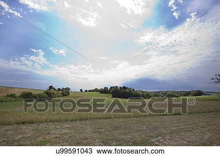 Stock Image - View of grassy land against cloudy sky. Fotosearch