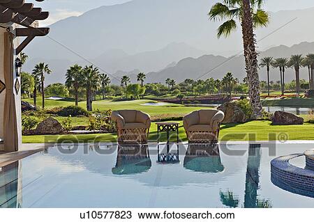 Stock Image - View of idyllic landscape with mansion swimming pool in foreground. Fotosearch