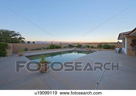 Stock Photo - View of landscape with swimming pool in foreground. Fotosearch
