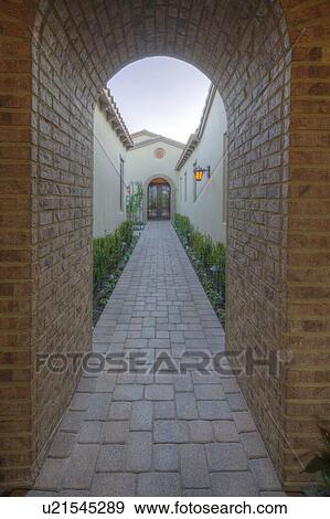 Stock Photo - View through archway down path to French doors of luxury home. Fotosearch