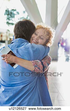 Wife reuniting with his husband in airport with lens flare View Large Photo Image Stock Photo - Wife reuniting with his husband in airport with lens flare. Fotosearch