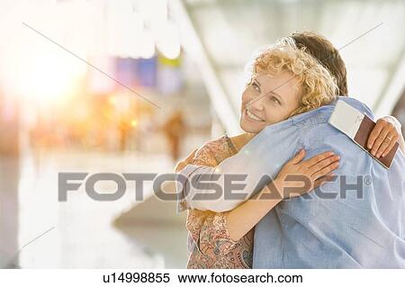 Wife reuniting with his husband in airport with yellow lens flare View Large Photo Image Stock Photography - Wife reuniting with his husband in airport with yellow lens flare. Fotosearch