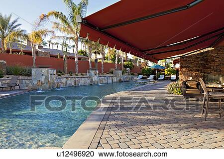 Stock Image - Window shade in patio near pool of luxury mansion. Fotosearch