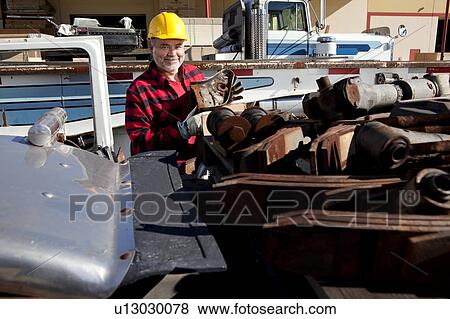 Stock Photo - Worker sorting scrap metal in front of Cargo truck. Fotosearch