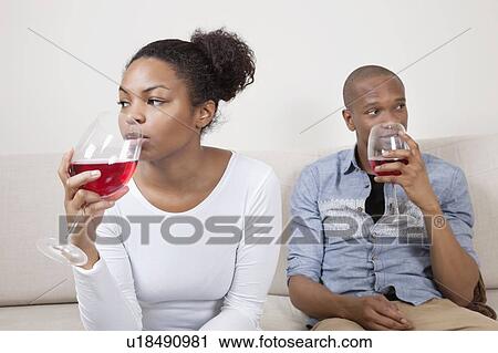 Stock Image - Young African American couple drinking red wine at home. Fotosearch
