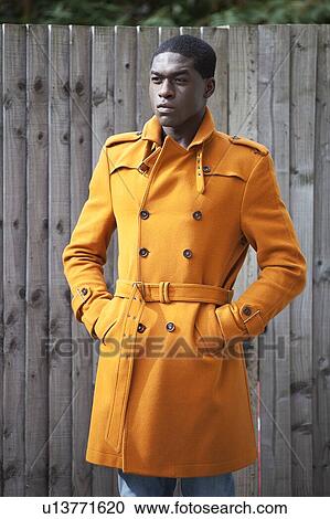 Young African American man in orange trench coat standing with hands in pockets View Large Photo Image Stock Image - Young African American man in orange trench coat standing with hands in pockets. Fotosearch