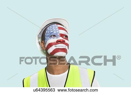 Stock Image - Young architect with American flag painted on face against colored background. Fotosearch