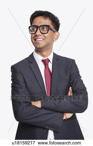 Stock Photo - Young Asian businessman with arms crossed day dreaming against white background. Fotosearch