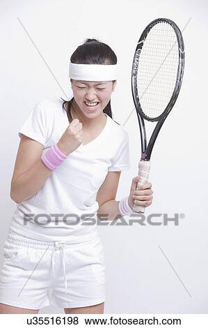 Stock Photo - Young Asian female tennis player celebrating her success against white background. Fotosearch