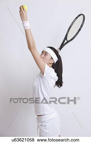 Young Asian female tennis player serving against white background View Large Photo Image Stock Photo - Young Asian female tennis player serving against white background. Fotosearch