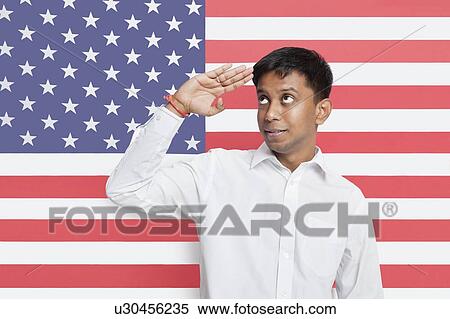 Stock Photography - Young Asian man in shirt saluting against American flag. Fotosearch