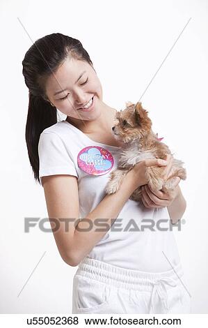 Young Asian woman carrying a puppy against white background View Large Photo Image Stock Photo - Young Asian woman carrying a puppy against white background. Fotosearch