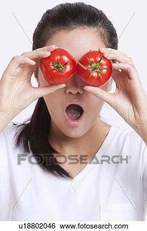 Young Asian woman covering her eyes with tomatoes against white background View Large Photo Image Stock Photograph - Young Asian woman covering her eyes with tomatoes against white background. Fotosearch