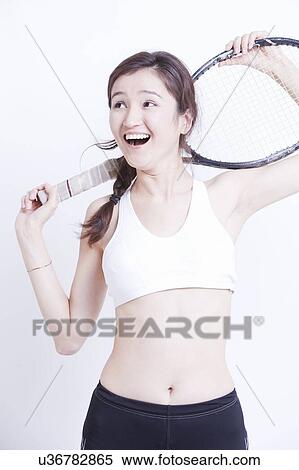 Young Asian woman holding tennis racket over her shoulder against white background View Large Photo Image Stock Photography - Young Asian woman holding tennis racket over her shoulder against white background. Fotosearch