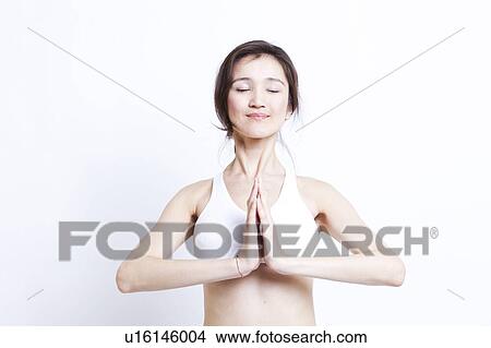 Young Asian woman in white sports bra meditating against white background View Large Photo Image Picture - Young Asian woman in white sports bra meditating against white background. Fotosearch