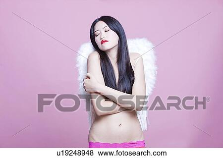 Young Asian woman wearing angel wings with arms crossed over pink background View Large Photo Image Stock Photo - Young Asian woman wearing angel wings with arms crossed over pink background. Fotosearch