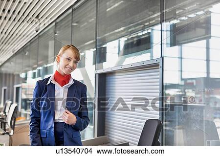 Picture - Young attractive airport security personnel standing against x-ray baggage scanner in airport. Fotosearch