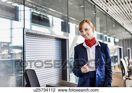 Stock Image - Young attractive airport security personnel standing against x-ray baggage scanner in airport. Fotosearch