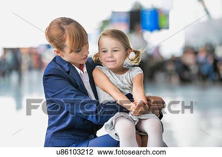 Stock Image - Young attractive airport staff talking to cute little girl in airport. Fotosearch