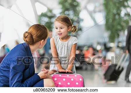 Stock Photo - Young attractive airport staff talking to cute little girl in airport. Fotosearch