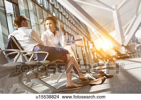 Picture - Young attractive airport staffs sitting while talking during break in airport. Fotosearch