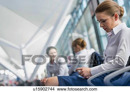 Young attractive airport staffs sitting while talking during break in airport View Large Photo Image Picture - Young attractive airport staffs sitting while talking during break in airport. Fotosearch