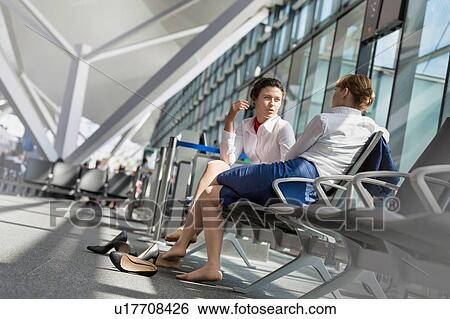 Stock Photograph - Young attractive airport staffs sitting while talking during break in airport. Fotosearch