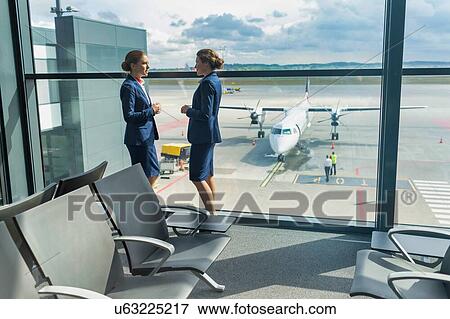 Young attractive airport staffs standing while talking during break in airport View Large Photo Image Stock Photo - Young attractive airport staffs standing while talking during break in airport. Fotosearch