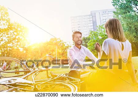 Young attractive business couple talking while sitting on the grass in park View Large Photo Image Stock Image - Young attractive business couple talking while sitting on the grass in park . Fotosearch