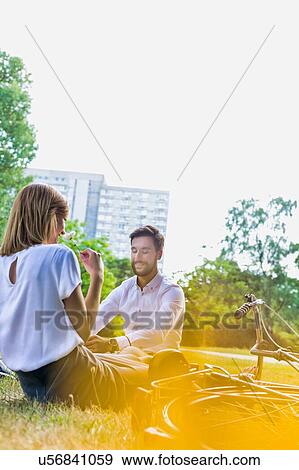Young attractive business couple talking while sitting on the grass in park View Large Photo Image Stock Photo - Young attractive business couple talking while sitting on the grass in park . Fotosearch