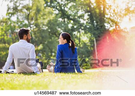 Young attractive businessman and businesswoman sitting on the grass while talking during break View Large Photo Image Stock Photo - Young attractive businessman and businesswoman sitting on the grass while talking during break. Fotosearch
