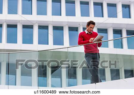 Stock Photo - Young attractive businessman using digital tablet. Fotosearch