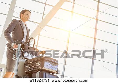 Young attractive businesswoman pushing baggage cart for check in at airport View Large Photo Image Stock Image - Young attractive businesswoman pushing baggage cart for check in at airport. Fotosearch