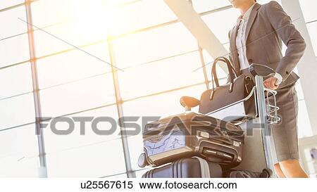 Young attractive businesswoman pushing baggage cart for check in at airport View Large Photo Image Stock Photography - Young attractive businesswoman pushing baggage cart for check in at airport. Fotosearch