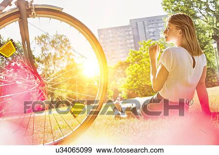 Young attractive businesswoman sitting on the grass while smelling white dandelion in park View Large Photo Image Stock Photo - Young attractive businesswoman sitting on the grass while smelling white dandelion in park. Fotosearch