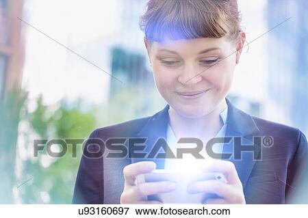 Stock Photo - Young attractive businesswoman smiling while using smartphone . Fotosearch