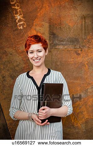 Young attractive businesswoman standing while holding document View Large Photo Image Stock Photo - Young attractive businesswoman standing while holding document . Fotosearch