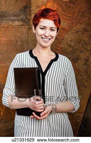 Stock Photo - Young attractive businesswoman standing while holding document . Fotosearch