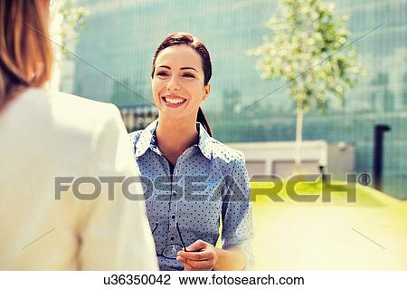 Stock Image - Young attractive businesswoman talking to her colleague. Fotosearch