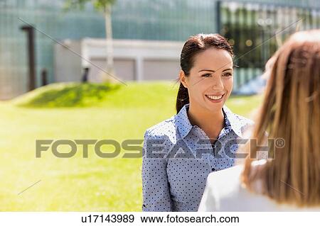 Stock Photo - Young attractive businesswoman talking to her colleague. Fotosearch