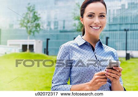 Young attractive businesswoman using smartphone outdoors View Large Photo Image Stock Photo - Young attractive businesswoman using smartphone outdoors. Fotosearch