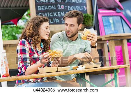 Young attractive couple eating hamburgers against food truck View Large Photo Image Stock Photography - Young attractive couple eating hamburgers against food truck. Fotosearch
