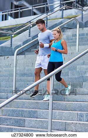 Stock Image - Young attractive couple exercising in stairs. Fotosearch